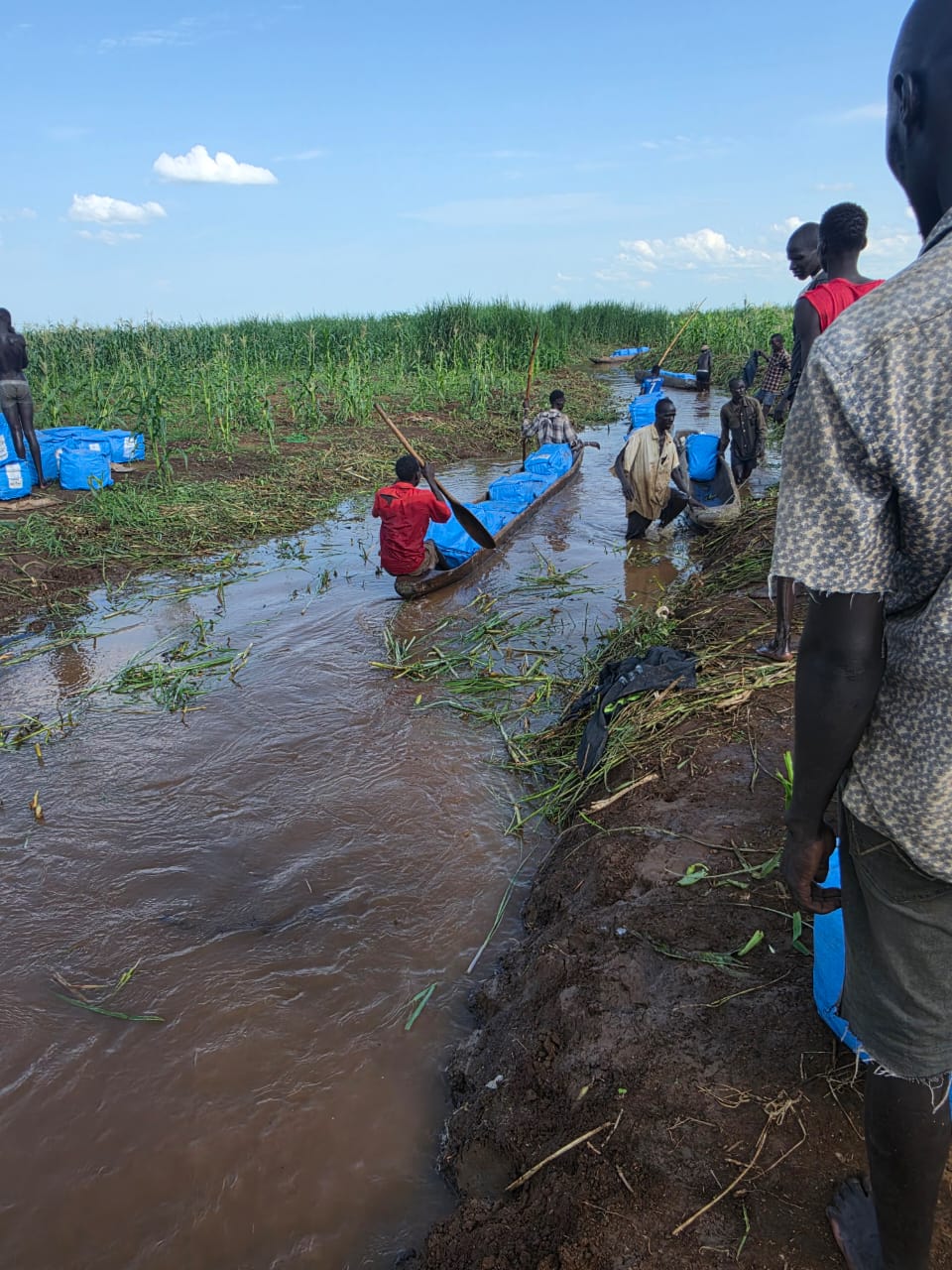 A loaded dugout canoe being paddled along a flooded channel towards villages in Ulang.